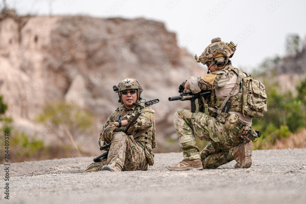 Soldiers in camo gear during a tactical operation with binoculars and rifles on a rocky terrain, showcasing military precision and readiness. Soldiers in camo gear during a tactical operation with binoculars and rifles on a rocky terrain, showcasing military precision and readiness.