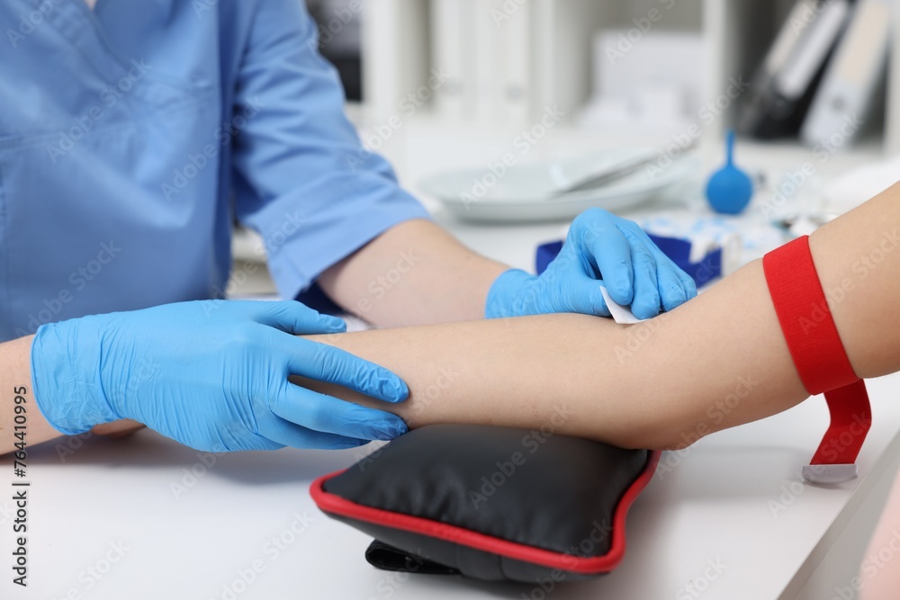 Laboratory testing. Doctor taking blood sample from patient at white table in hospital, closeup Laboratory testing. Doctor taking blood sample from patient at white table in hospital, closeup