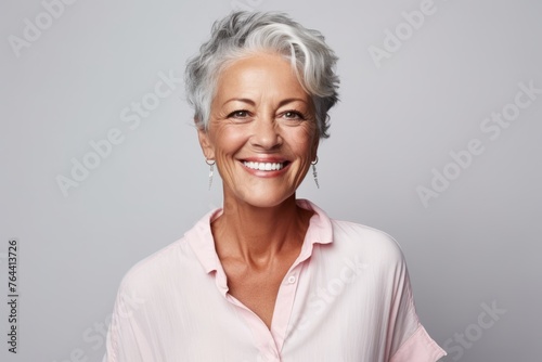 Portrait of a happy senior woman smiling at camera against grey background