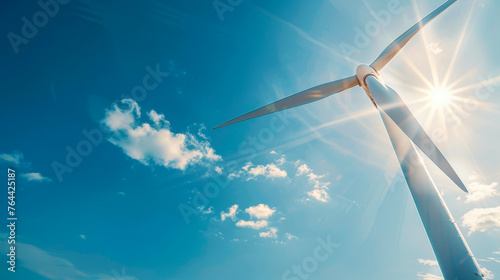 A wind turbine is standing tall in the sky, with the sun shining brightly on it. Concept of energy and power, as the wind turbine harnesses the sun's energy to generate electricity