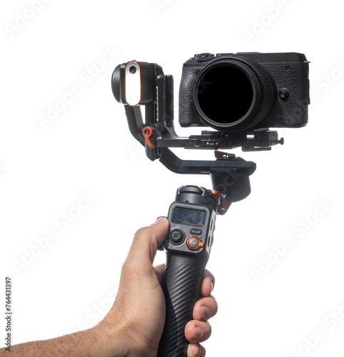 A person is holding a camera gimbal on a white background.