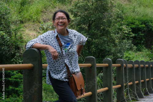 Woman smiling and leaning on a bridge railing over a river in Yogyakarta photo