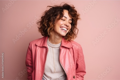 Portrait of a beautiful young woman with curly hair laughing against pink background
