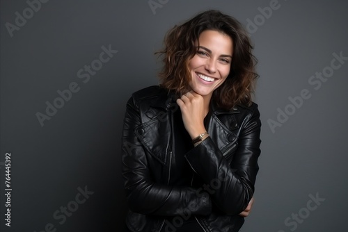 Portrait of a beautiful young woman in leather jacket smiling at camera © Inigo