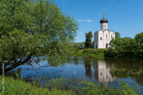 View of the Church of the Intercession on the Nerl on the shore of Floodplain Lake on a sunny summer day, Bogolyubovo village, Vladimir region, Russia photo