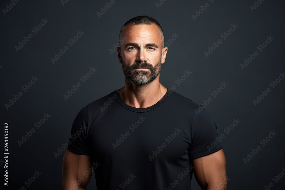 Portrait of a handsome mature man with beard and mustache in black t-shirt on dark background