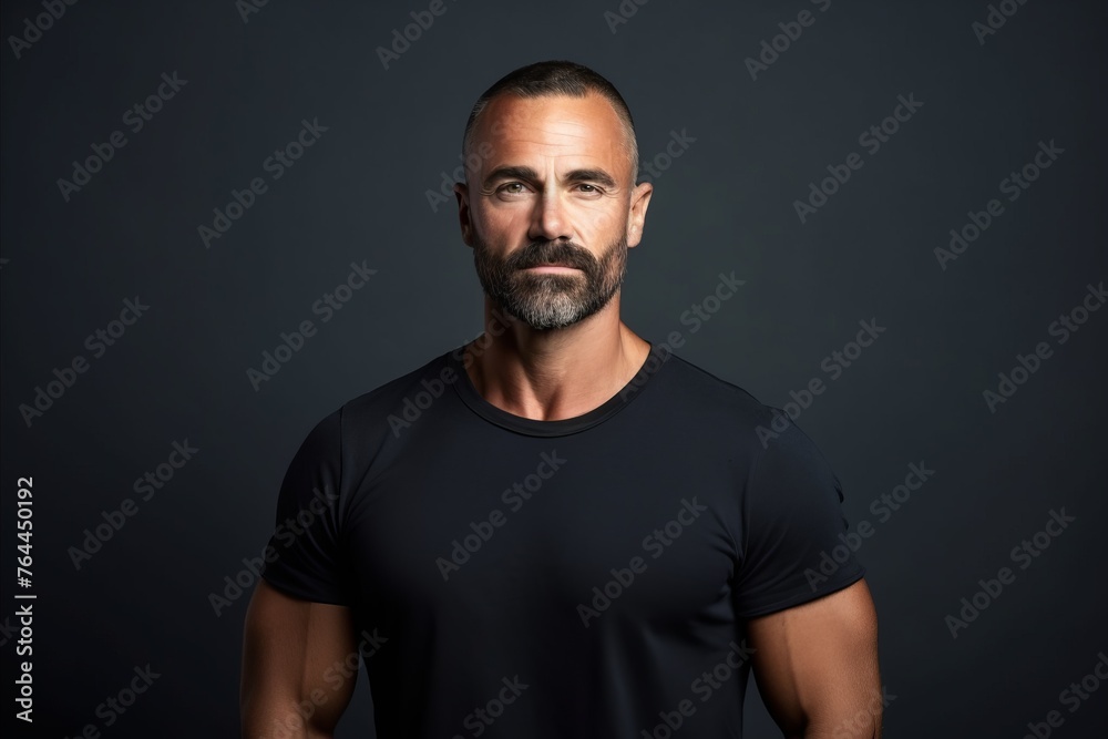 Portrait of a handsome mature man with beard and mustache in black t-shirt on dark background Portrait of a handsome mature man with beard and mustache in black t-shirt on dark background