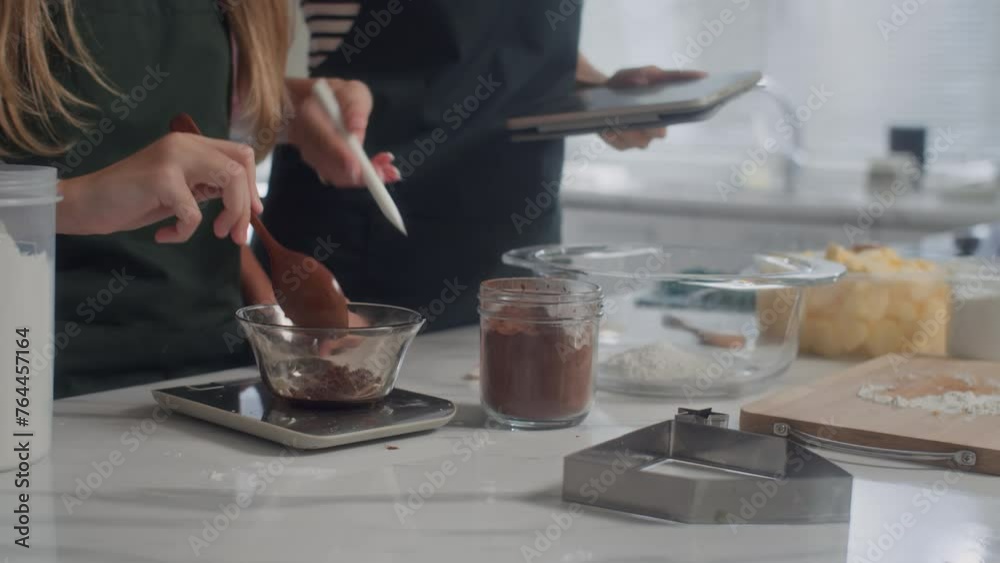 Cropped shot of family making dough for cookies according recipe on tablet Cropped shot of family making dough for cookies according recipe on tablet