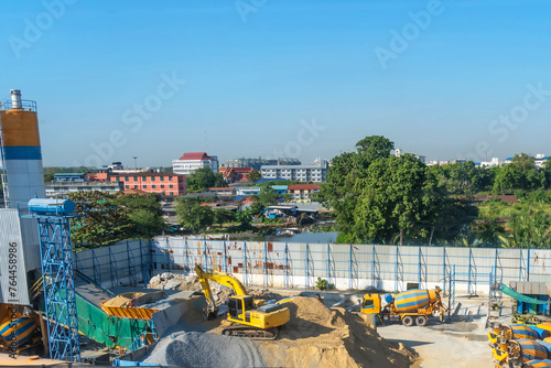 Asphalt and cement factory. Large piles of construction sand, gravel, limestone quarry, mining rocks used for asphalt production, building. Heavy machinery in parking lot ready to work