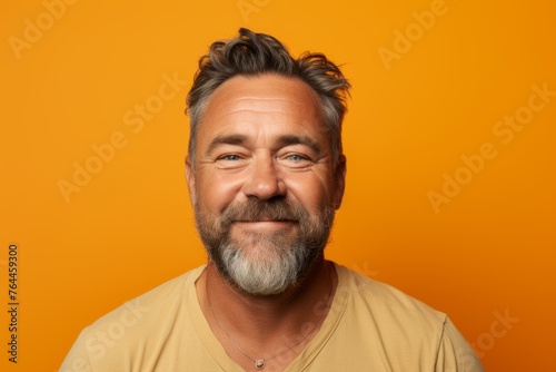 Portrait of happy mature man with beard and mustache on orange background