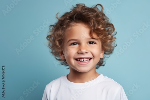 Portrait of a cute smiling little boy with curly hair on a blue background