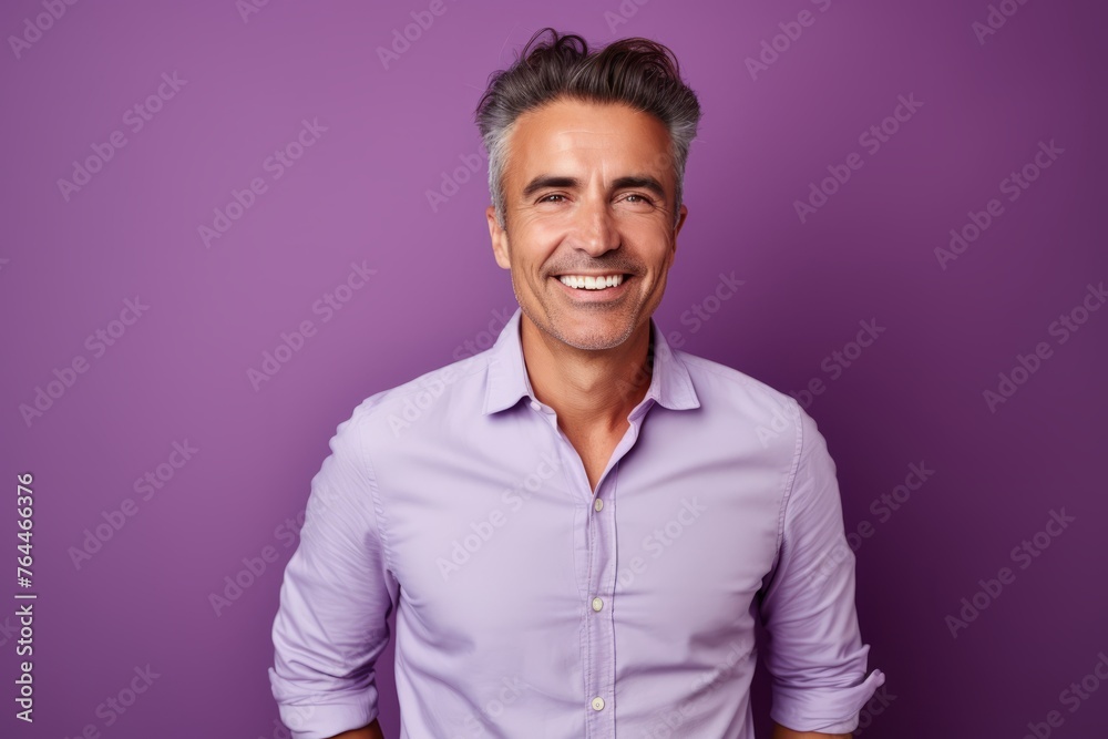 Portrait of a handsome mature man smiling and looking at camera against purple background Portrait of a handsome mature man smiling and looking at camera against purple background