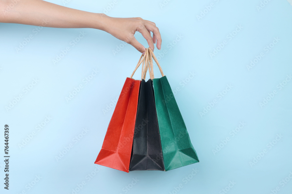 Hand Holds Colorful Shopping Bags Isolated on Blue Background 