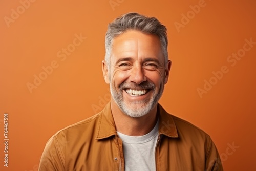 Portrait of a happy senior man smiling over orange background. Men's beauty, fashion. © Inigo