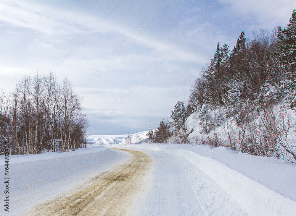 Fototapeta premium Walking on a snow-covered roadbed in a mountainous area, treated with a sand mixture from anti-skid.