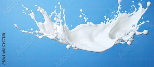 A dynamic and visually appealing image of a splash of milk captured in motion against a vivid blue background