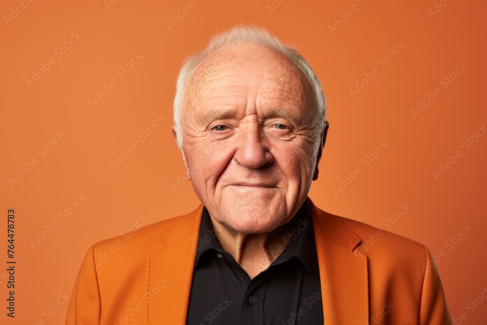 Portrait of an elderly man. Studio shot over orange background.