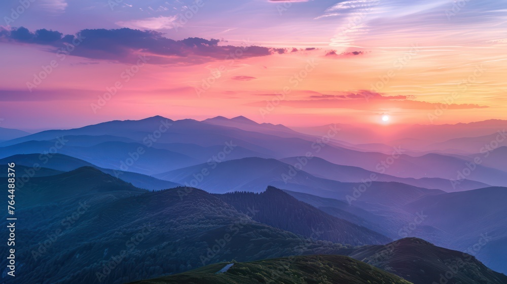 Obraz premium The image captures a stunning sunset with vibrant hues of pink, purple, and blue cascading over multiple mountain ranges, creating a tranquil atmosphere