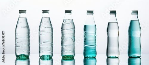 A straight row of transparent plastic water bottles with no liquid inside, isolated on a white background