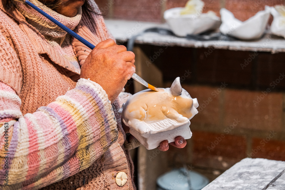 elderly latin artisan woman painting a plaster sculpture in latin america - entrepreneurship concept