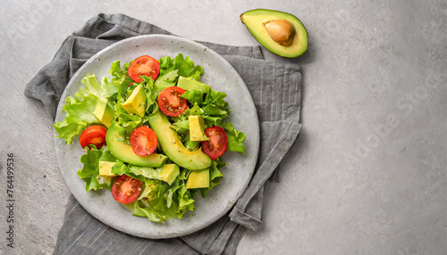 green salad, avocado salad. top view of avocado salad with lettuce and tomatoes on grey plate, healthy salad, copy space