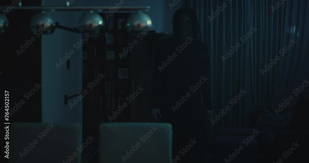 Horror scene - a dark and ominous demon walks through a ghastly living room at night