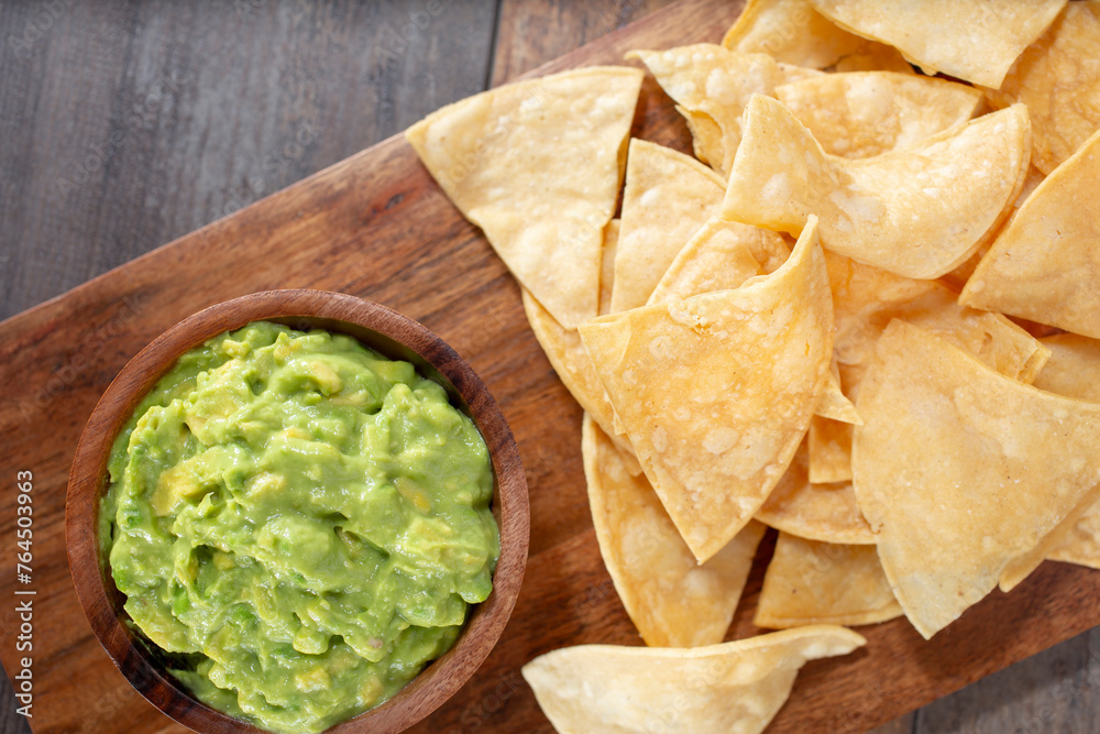 A top down view of a tray of guacamole and chips.