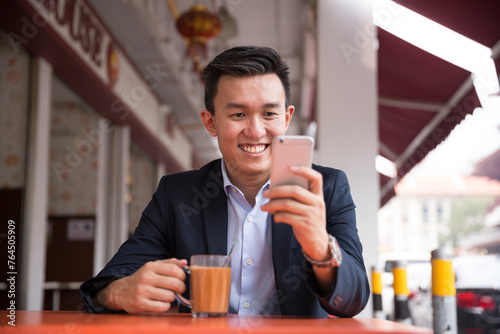 Businessman drinking a cup of tea in an Asian food court.