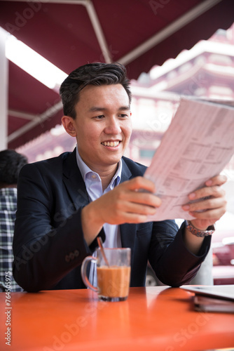 Asian businessman reading in a food court.