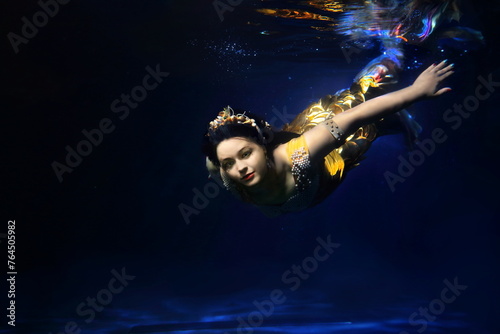 A girl in a mermaid costume swims underwater