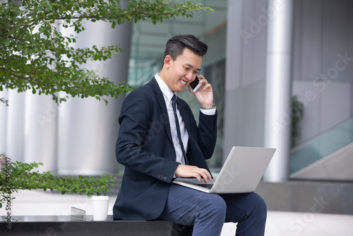 Asian business Man using his laptop outdoors.