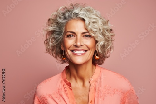 Portrait of a beautiful middle aged woman with curly hair on a pink background