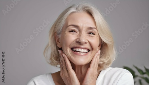Happy beautiful blonde older mature lady touching facial skin looking away with perfect toothy smile laughing enjoying elderly beauty care thinking on good skincare result