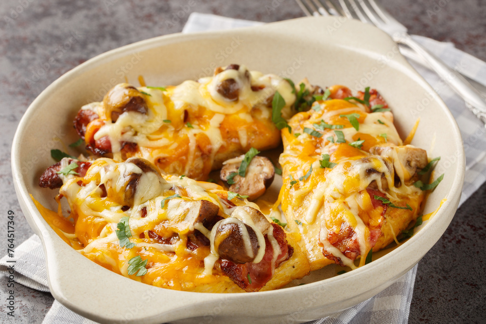 Chicken breasts are topped with a honey mustard sauce, bacon, cheese, and mushrooms closeup in the baking dish on the table. Horizontal Chicken breasts are topped with a honey mustard sauce, bacon, cheese, and mushrooms closeup in the baking dish on the table. Horizontal