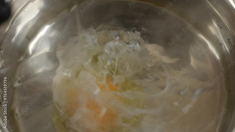 Cooking poached egg. Putting raw egg in boiling water in saucepan