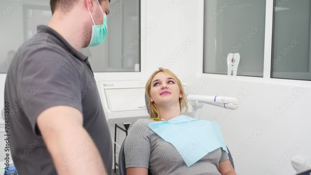 Professional dentist consult patient after dental treatment. Happy young woman thanks male doctor after UV whitening teeth. Female patient talking with stomatologist in the modern dental office. Professional dentist consult patient after dental treatment. Happy young woman thanks male doctor after UV whitening teeth. Female patient talking with stomatologist in the modern dental office.