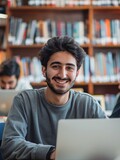 A grinning college student studying in a library.