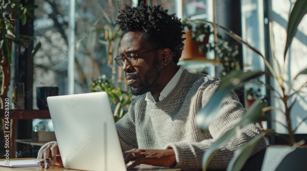 A man sitting at a table using a laptop computer. Suitable for technology concepts A man sitting at a table using a laptop computer. Suitable for technology concepts