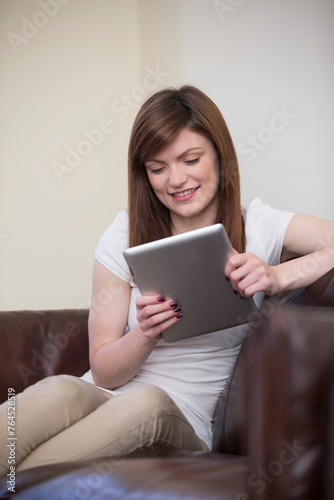 Female student using a tablet computer at home.