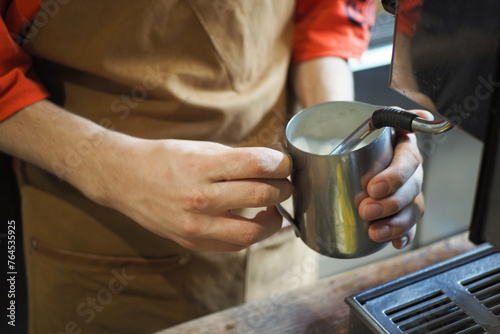  preparing fresh coffee, holding pitcher for steaming milk. Preparation and service concept