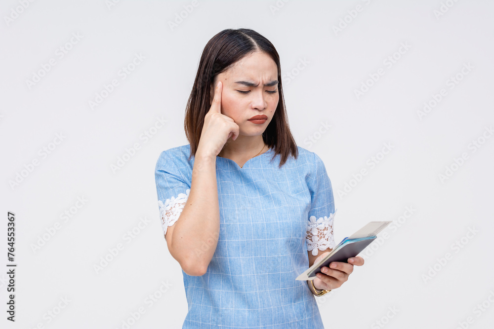 Asian woman in blue holding passport and boarding pass, thinking hard Asian woman in blue holding passport and boarding pass, thinking hard