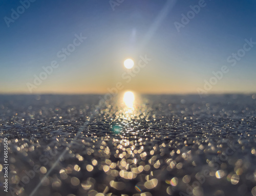 Defocus natural background. Sunset on the background of a frozen lake. Bokeh. Defocus lights. Ice. Winter. The sun's rays.