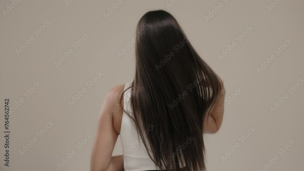 Brunette girl with long straight hair, rear view in the studio on a light background. Brunette girl with long straight hair, rear view in the studio on a light background.
