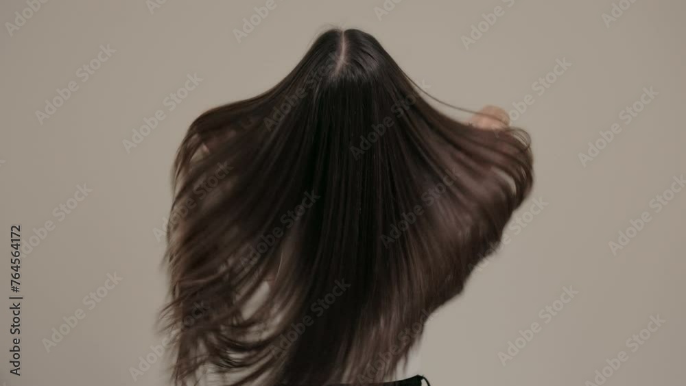Brunette girl with long straight hair, rear view in the studio on a light background.