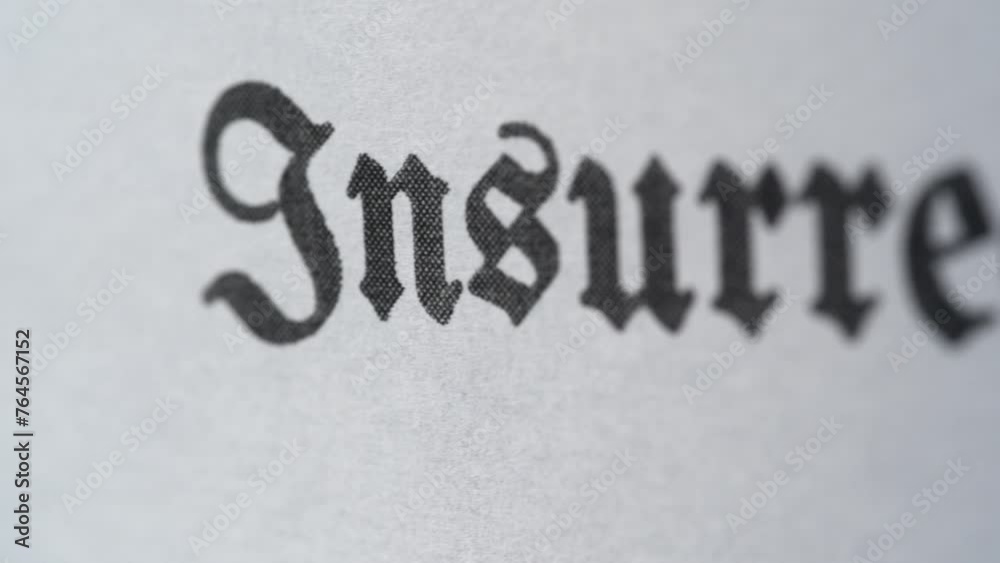 An ECU macro tracking shot of the word Insurrection printed on paper in a vintage font in shallow focus An ECU macro tracking shot of the word Insurrection printed on paper in a vintage font in shallow focus