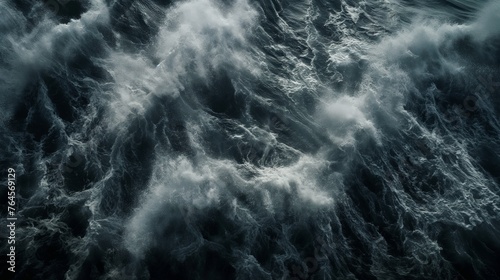 Dark and moody aerial view of tumultuous sea waves, creating a sense of mystery and power.