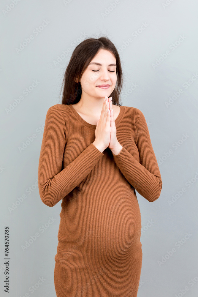 Obraz premium cute pregnant woman praying on colored background isolated