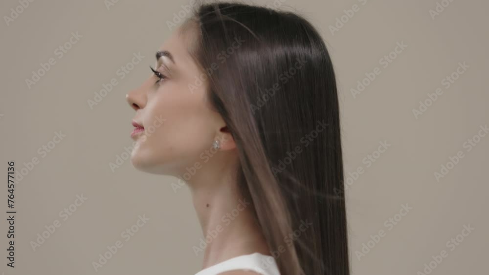 A brunette girl with long straight hair poses in the studio against a light background. A brunette girl with long straight hair poses in the studio against a light background.