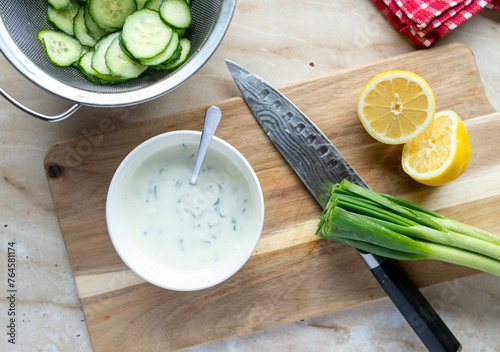 Cucumber salad, making, preparation, ingredients salad sauce on wooden cutting board with knife