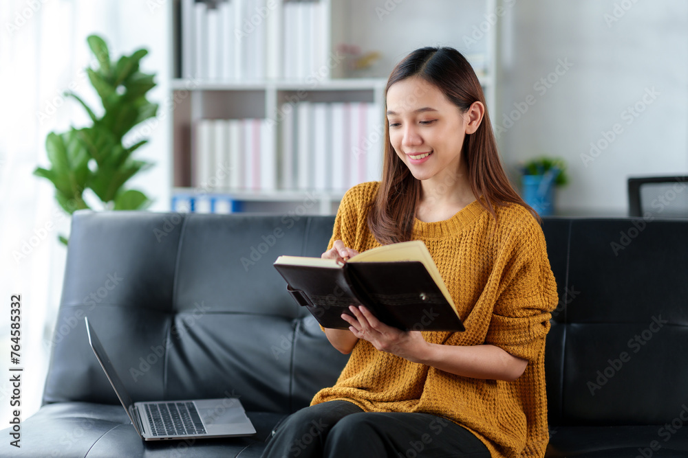 A woman is sitting on a couch with a laptop and a notebook A woman is sitting on a couch with a laptop and a notebook